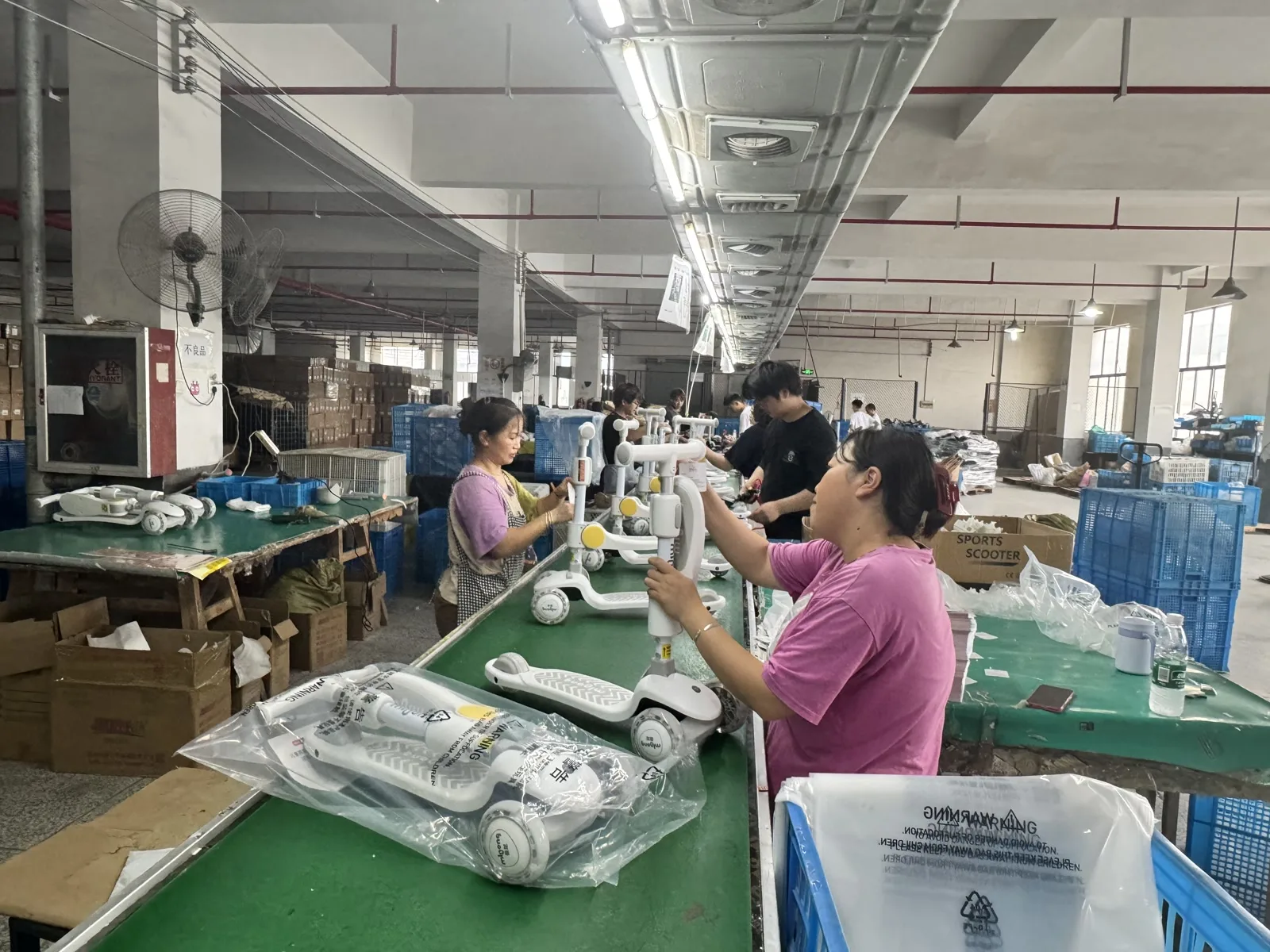 Workers assembling kids scooters on the production line